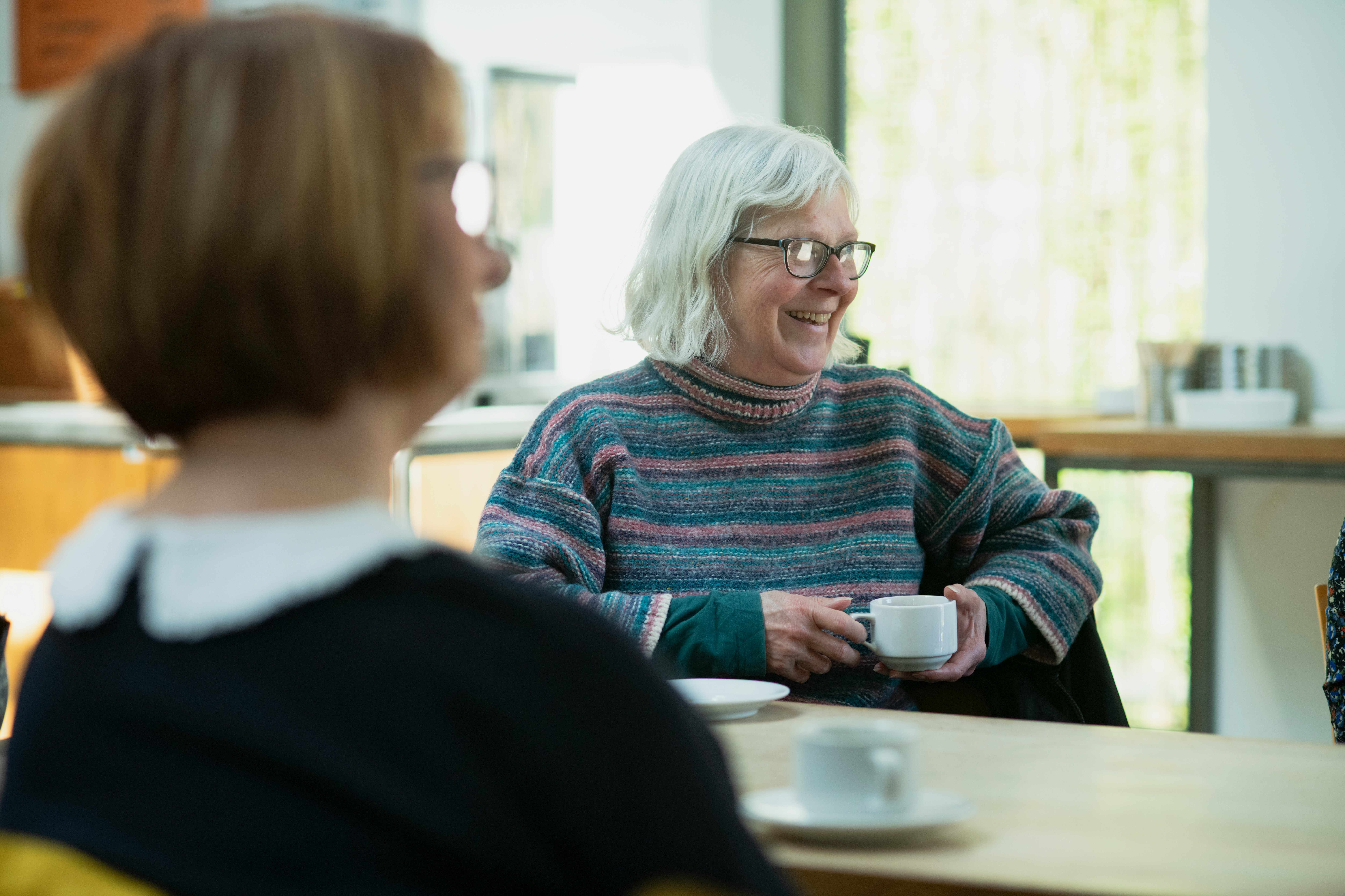 two older people smiling over coffee