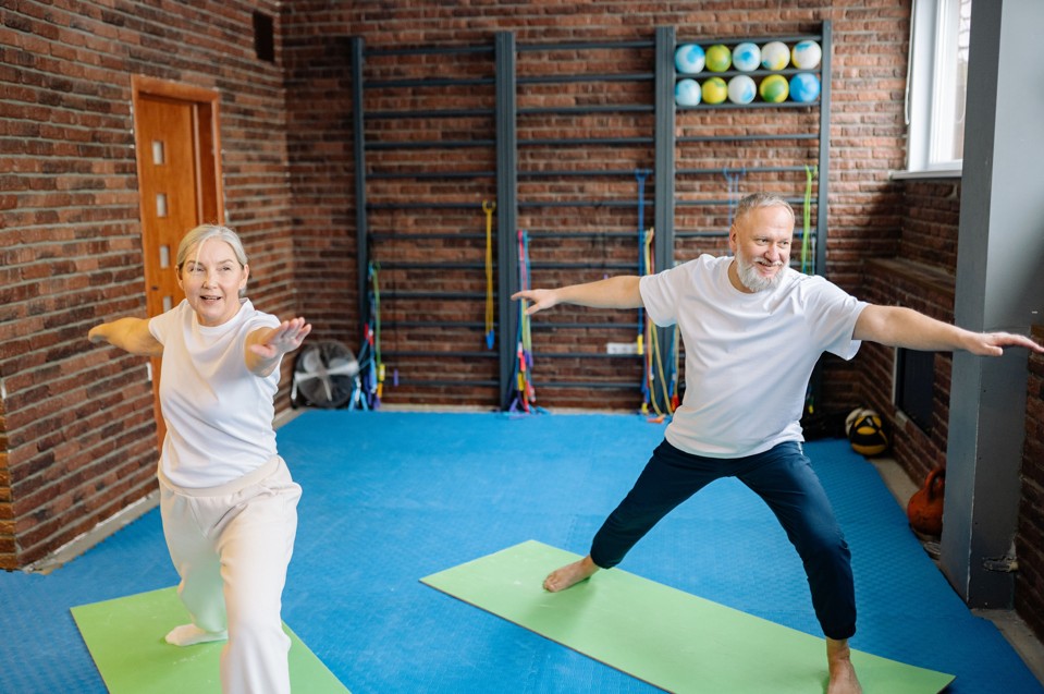 Elderly couple performing yoga stretches on mat