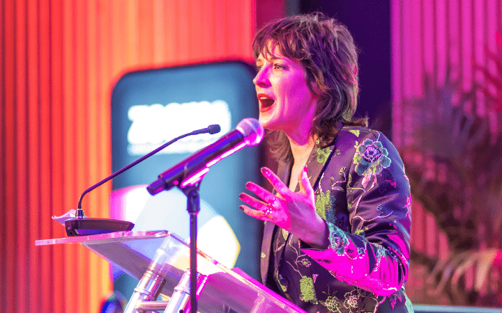 woman speaking into a microphone to a crowd