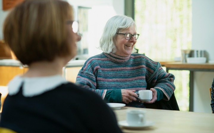 two older people smiling over coffee