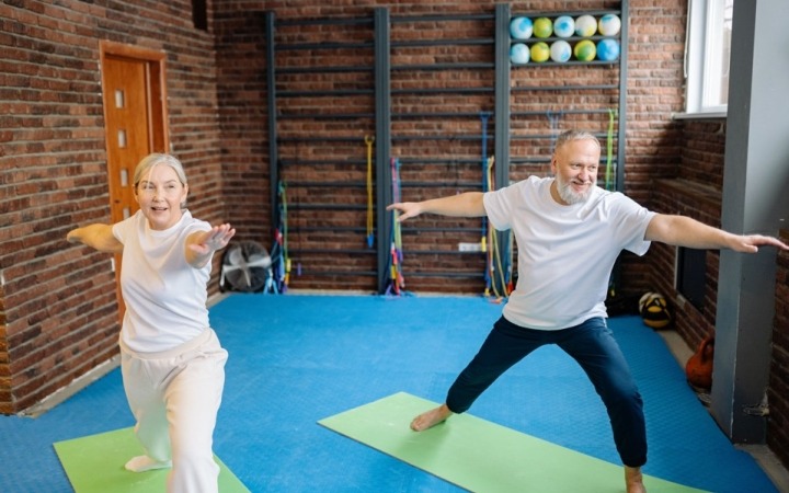 Elderly couple performing yoga stretches on mat